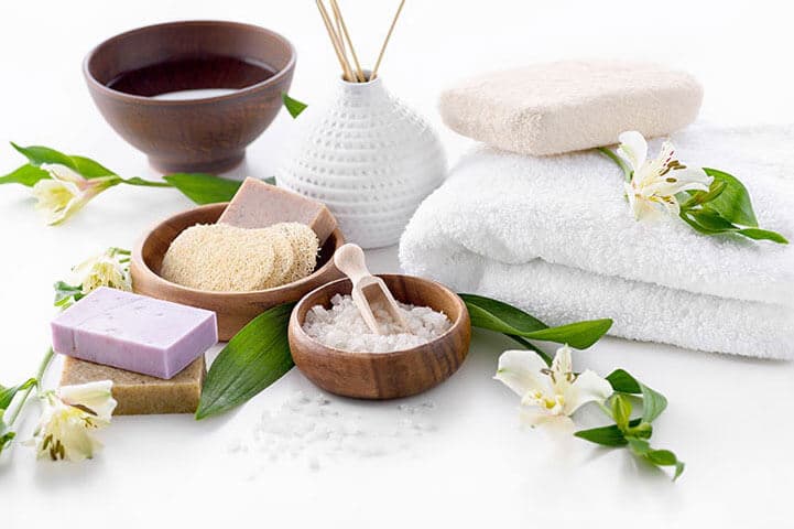 Bath salts, soaps, a loofah and towels laid out for a body treatment